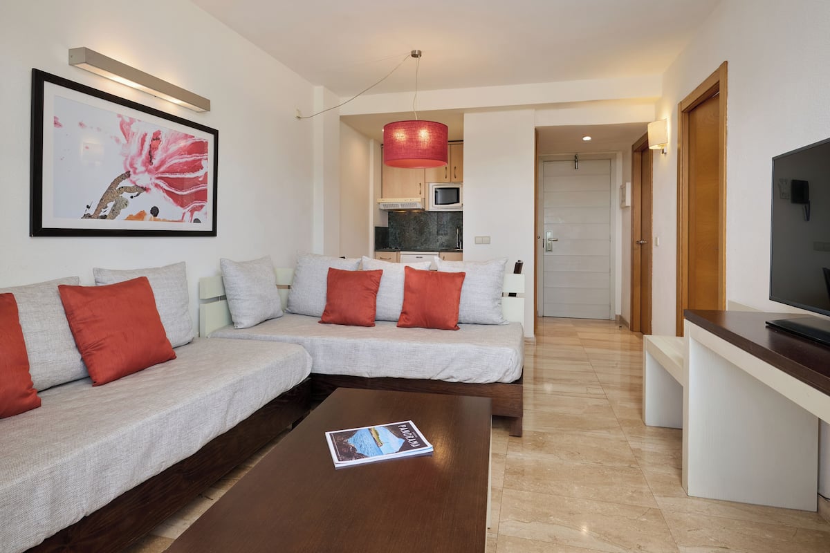 Una sala moderna con un sofá modular, una mesa de centro y un televisor.