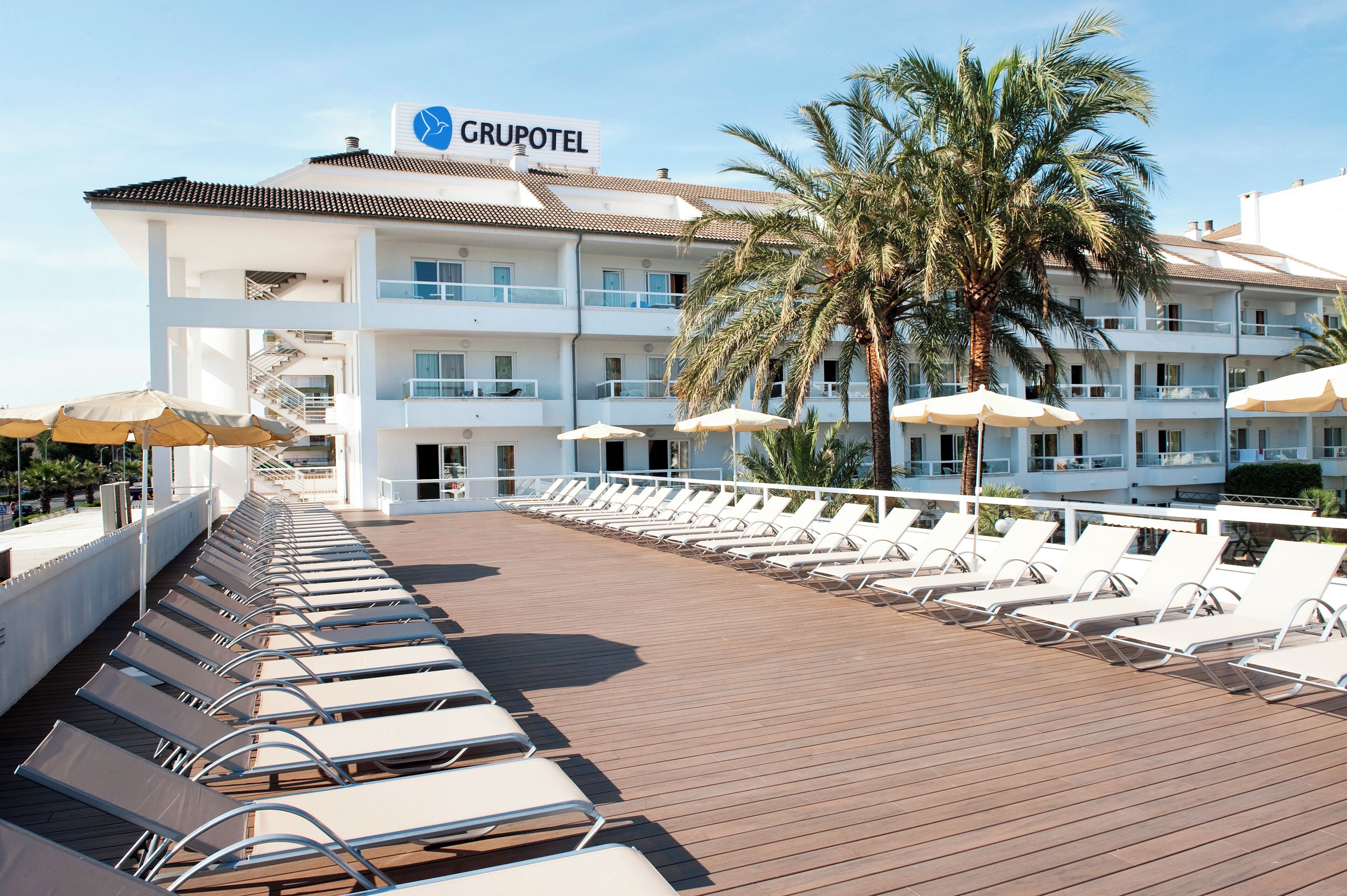 Un hotel con piscina, tumbonas y palmeras.