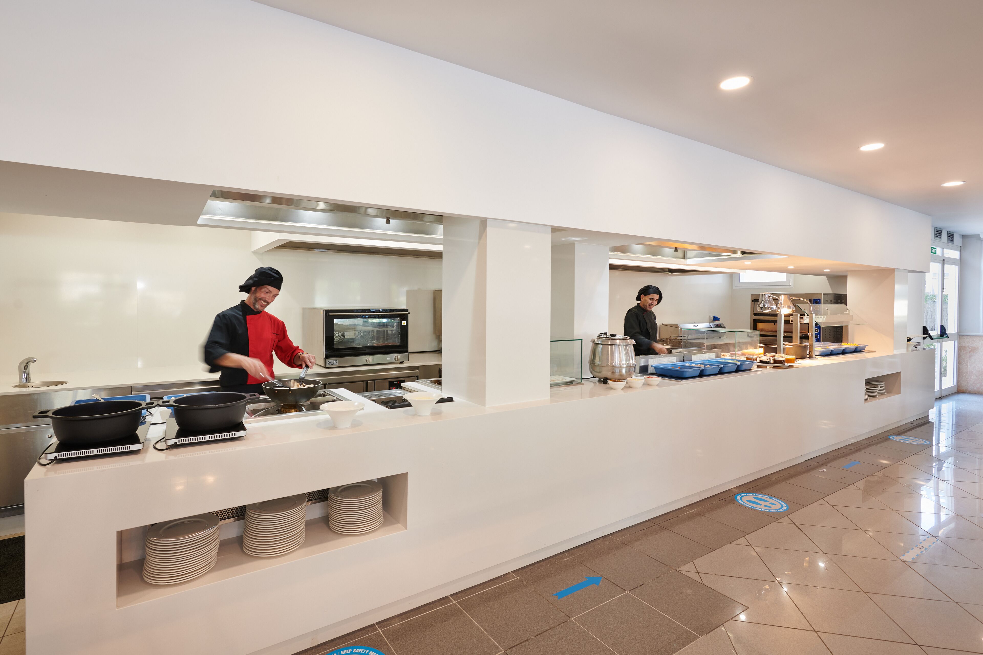 Un espace cuisine moderne doté d’appareils électroménagers en acier inoxydable, d’un buffet et d’une disposition épurée et spacieuse.