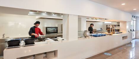 Et moderne køkkenområde med stålemhætter, et buffetbord og en ren, rummelig indretning.