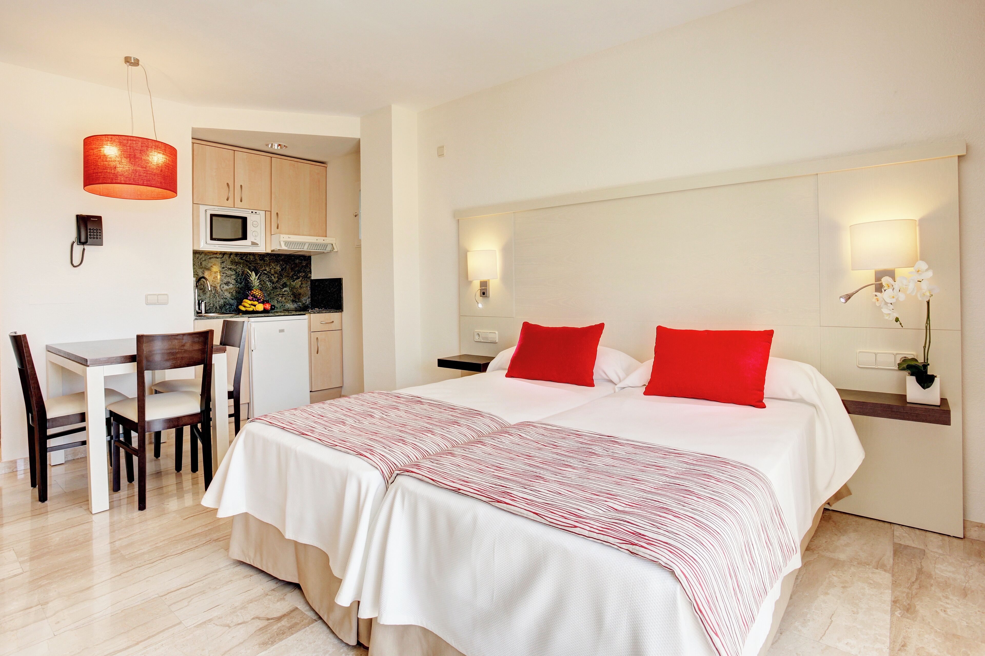 Une chambre d’hôtel équipée d’un lit, d’un bureau, d’un four à micro-ondes et d’un petit coin cuisine.