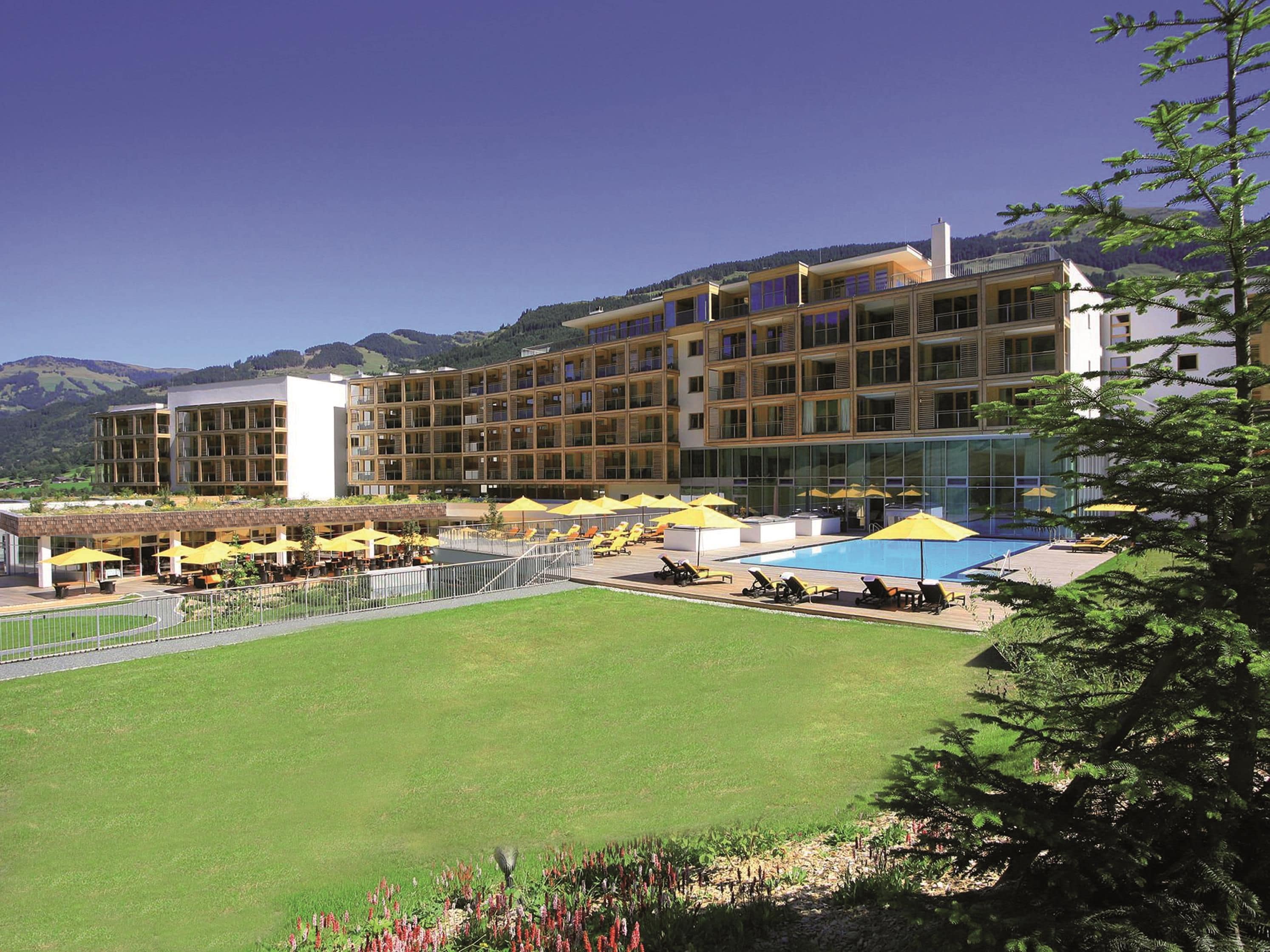 A hotel with multiple floors, outdoor pool area, and a well-maintained lawn.
