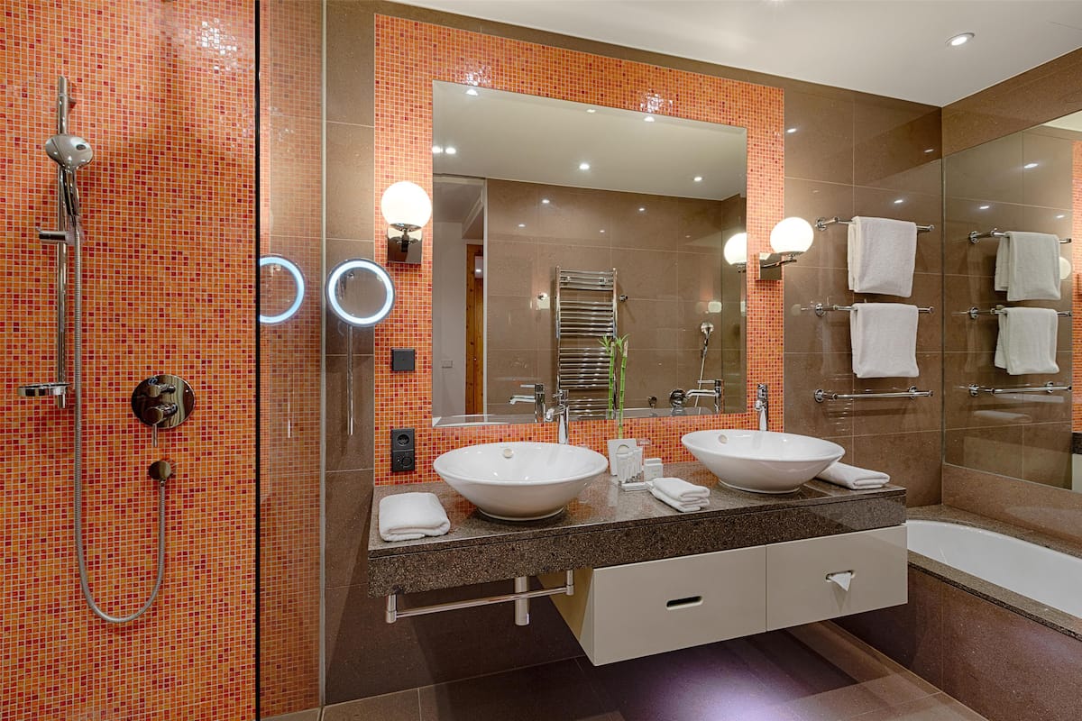 A modern bathroom with two sinks, a glass shower enclosure, and a large mirror.