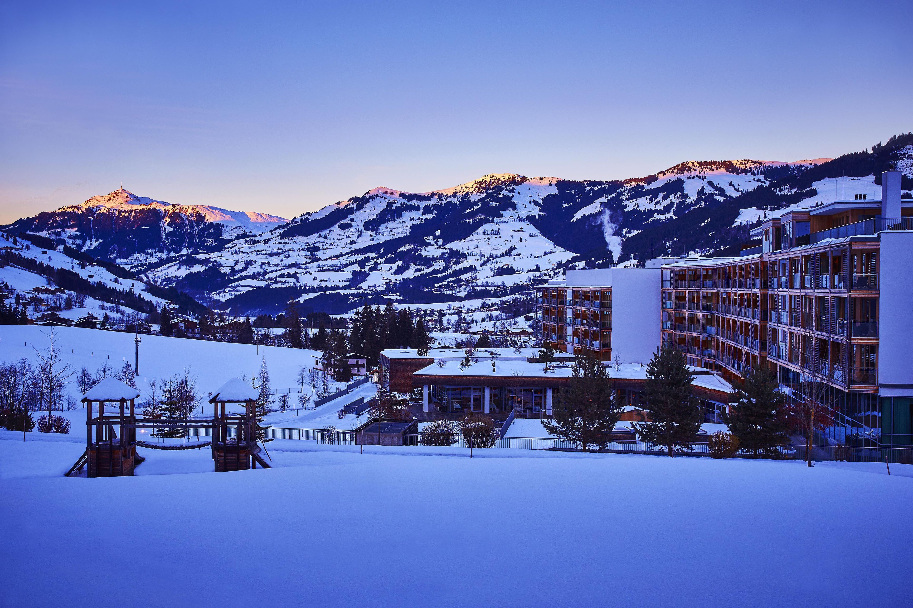 Un hotel con vistas a la montaña, paisaje nevado y un telesilla.