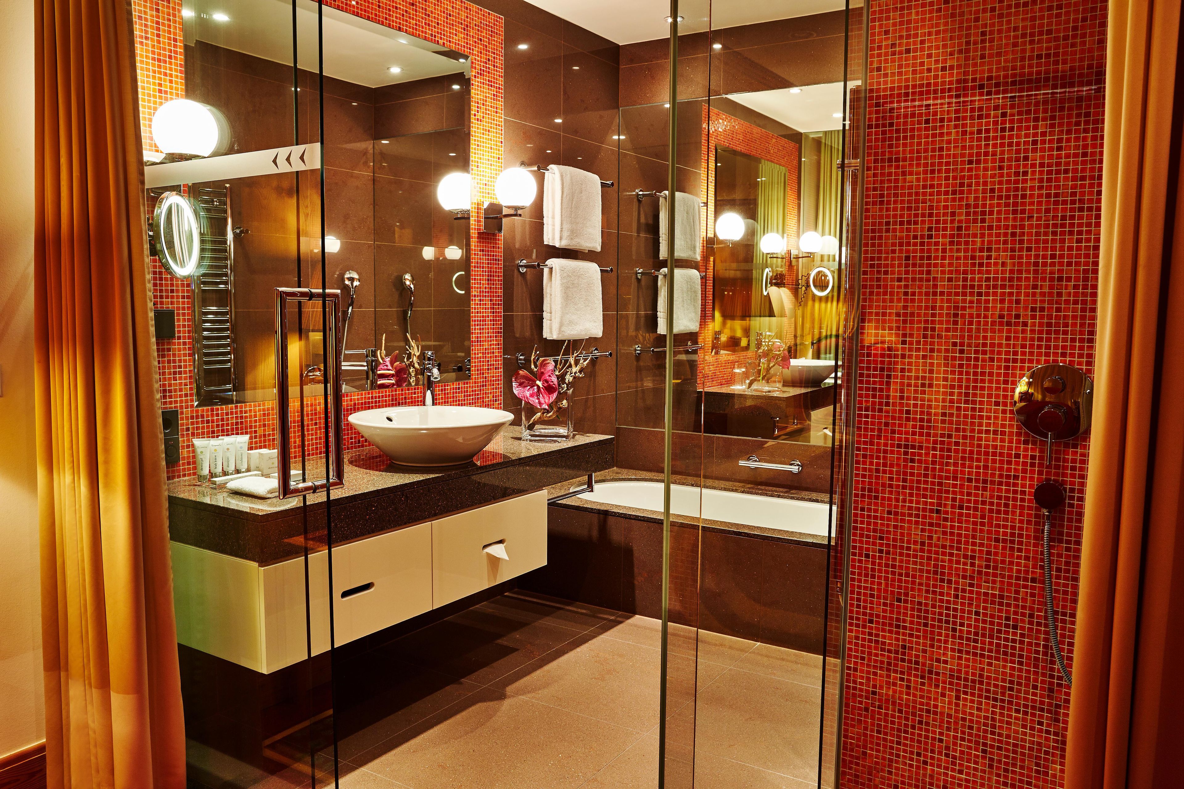 A modern bathroom with a large mirror, a sink, and a bathtub.