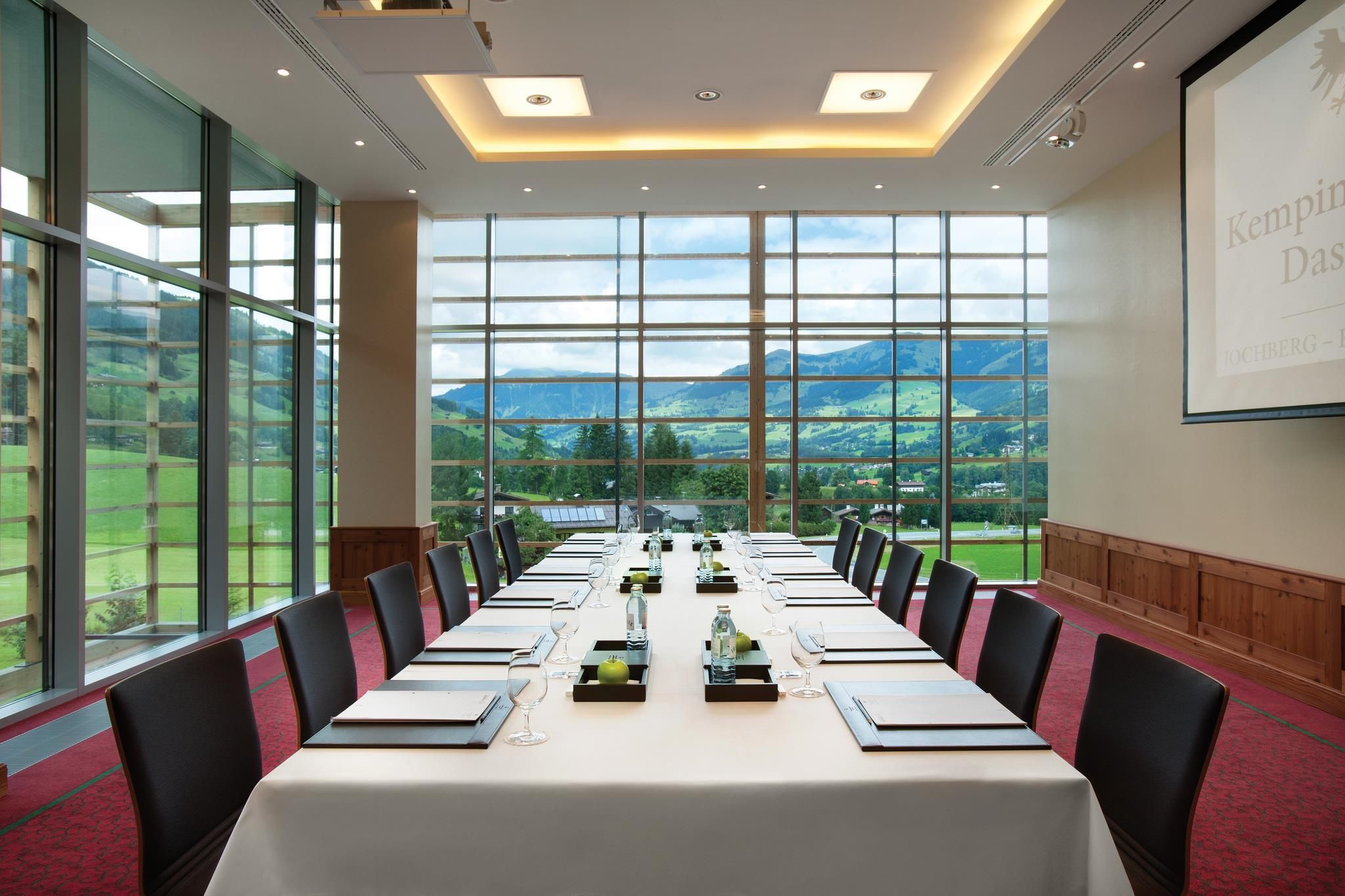 Un salón de conferencias con una mesa larga, sillas y un amplio ventanal con vista a la montaña.