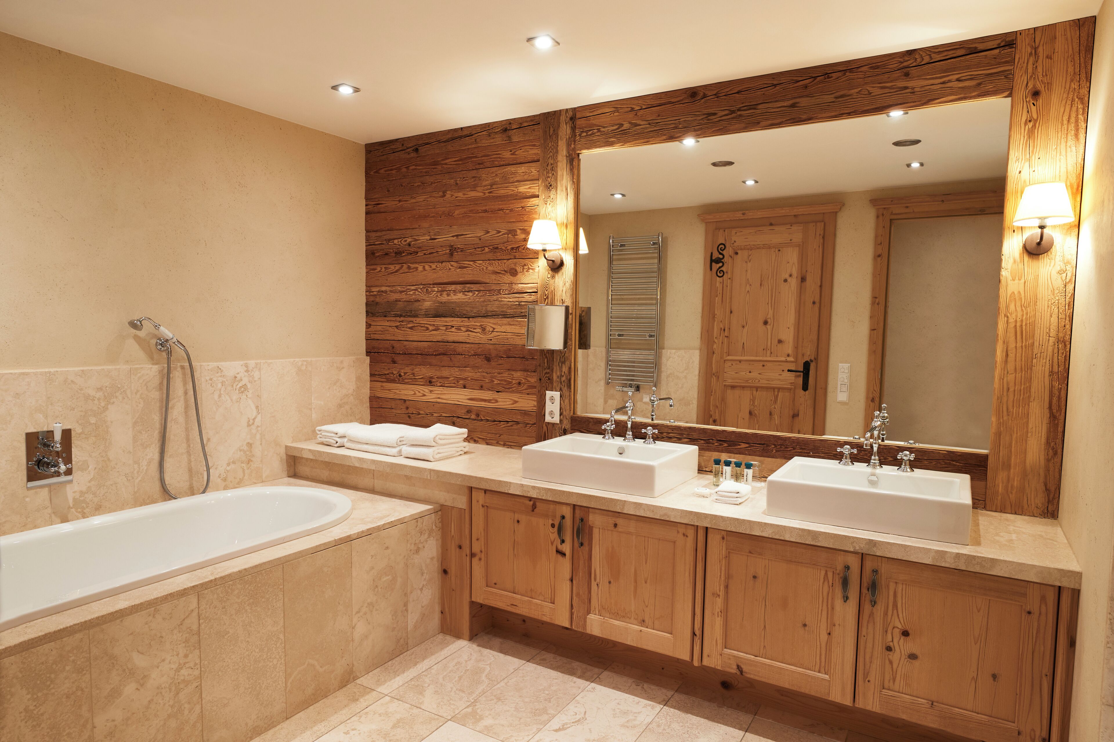Ein modernes Badezimmer mit einem Holzbadezimmermöbel, zwei Waschbecken, einer Badewanne und einem großen Spiegel.