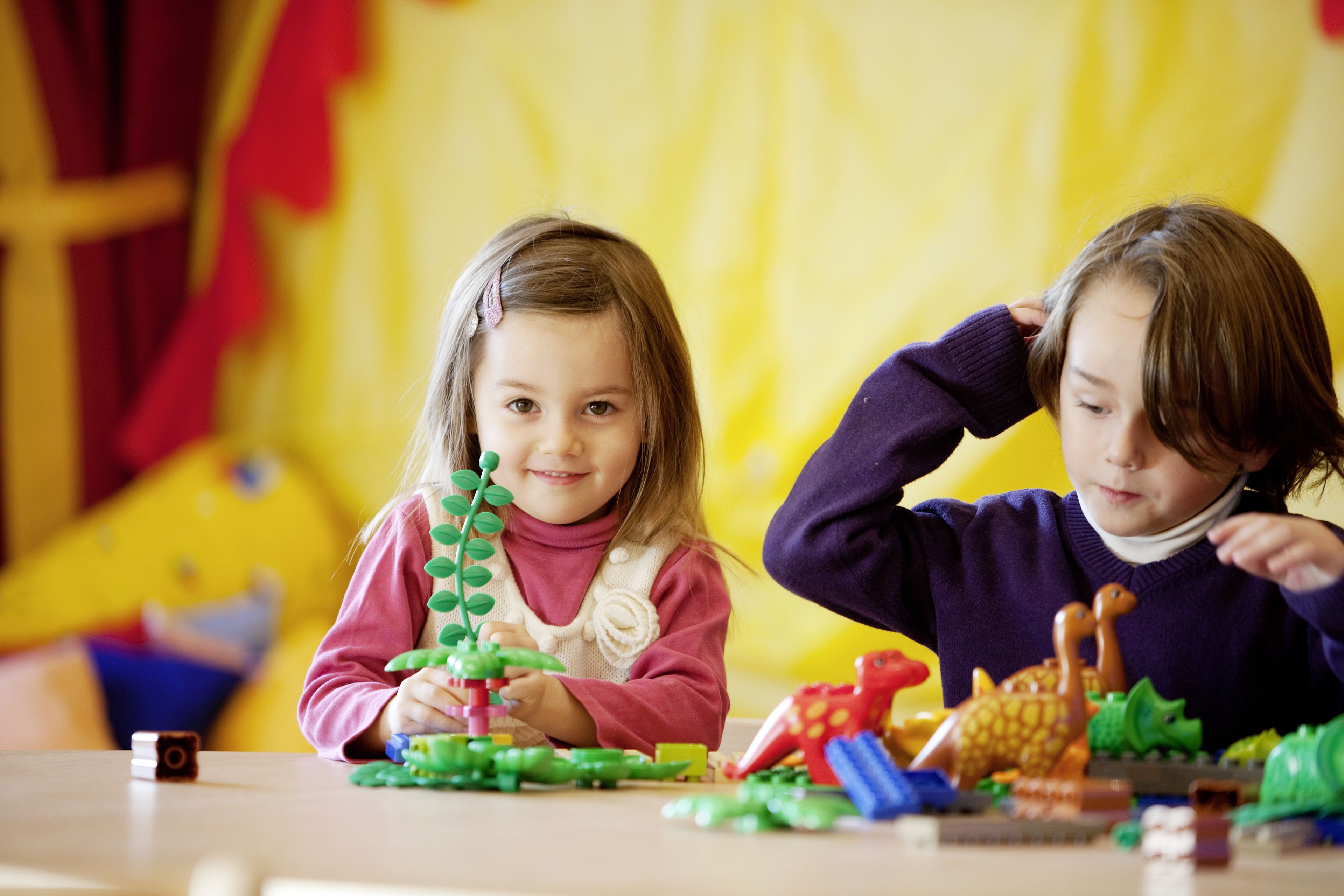 Dos niños jugando con juguetes en una mesa.