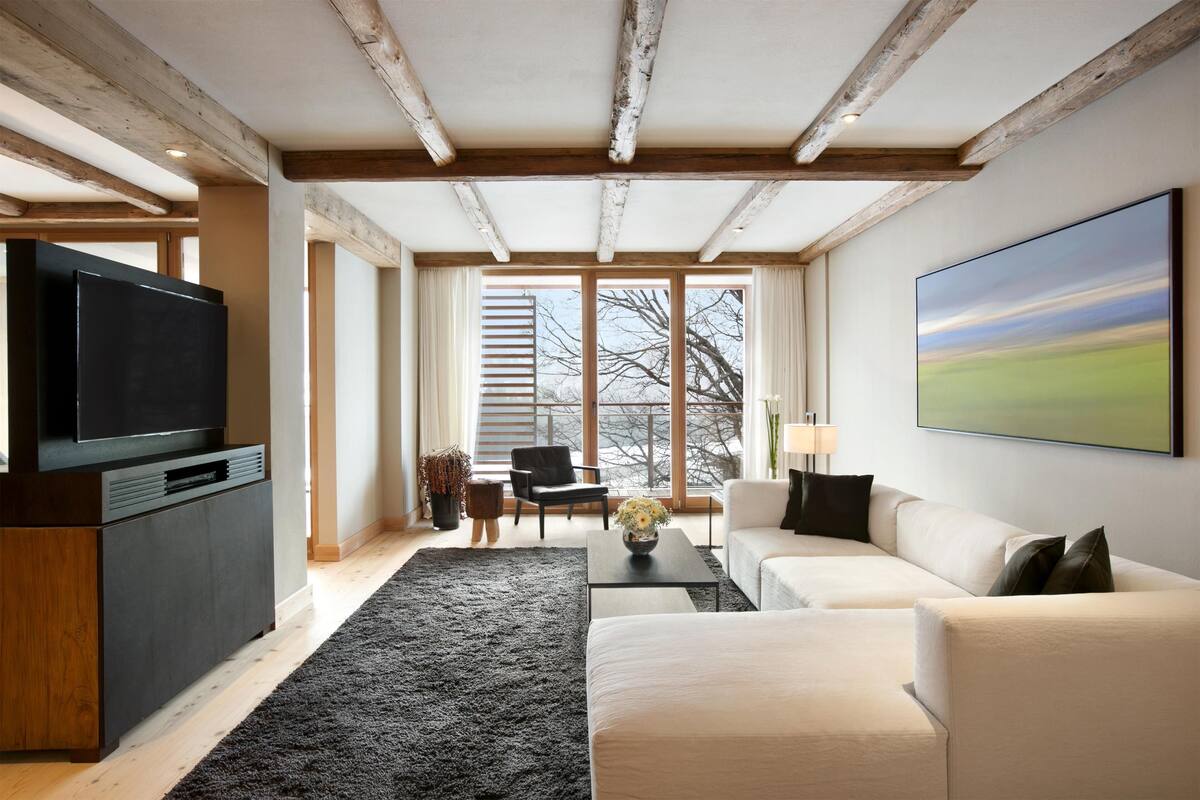 A modern living room with a large TV, a sofa, a coffee table, and a painting on the wall.