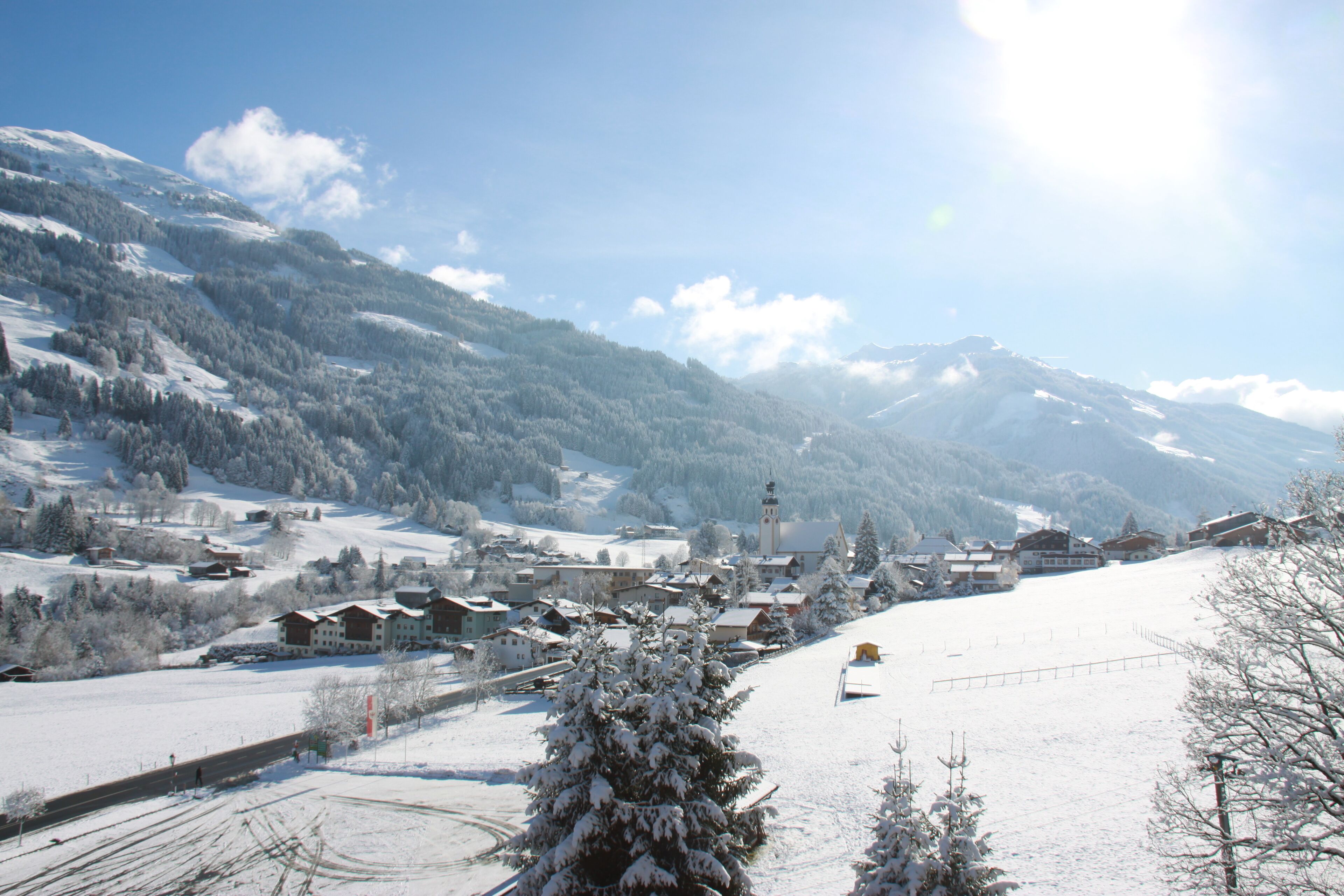 A snow-covered village with buildings and a church, surrounded by mountains.