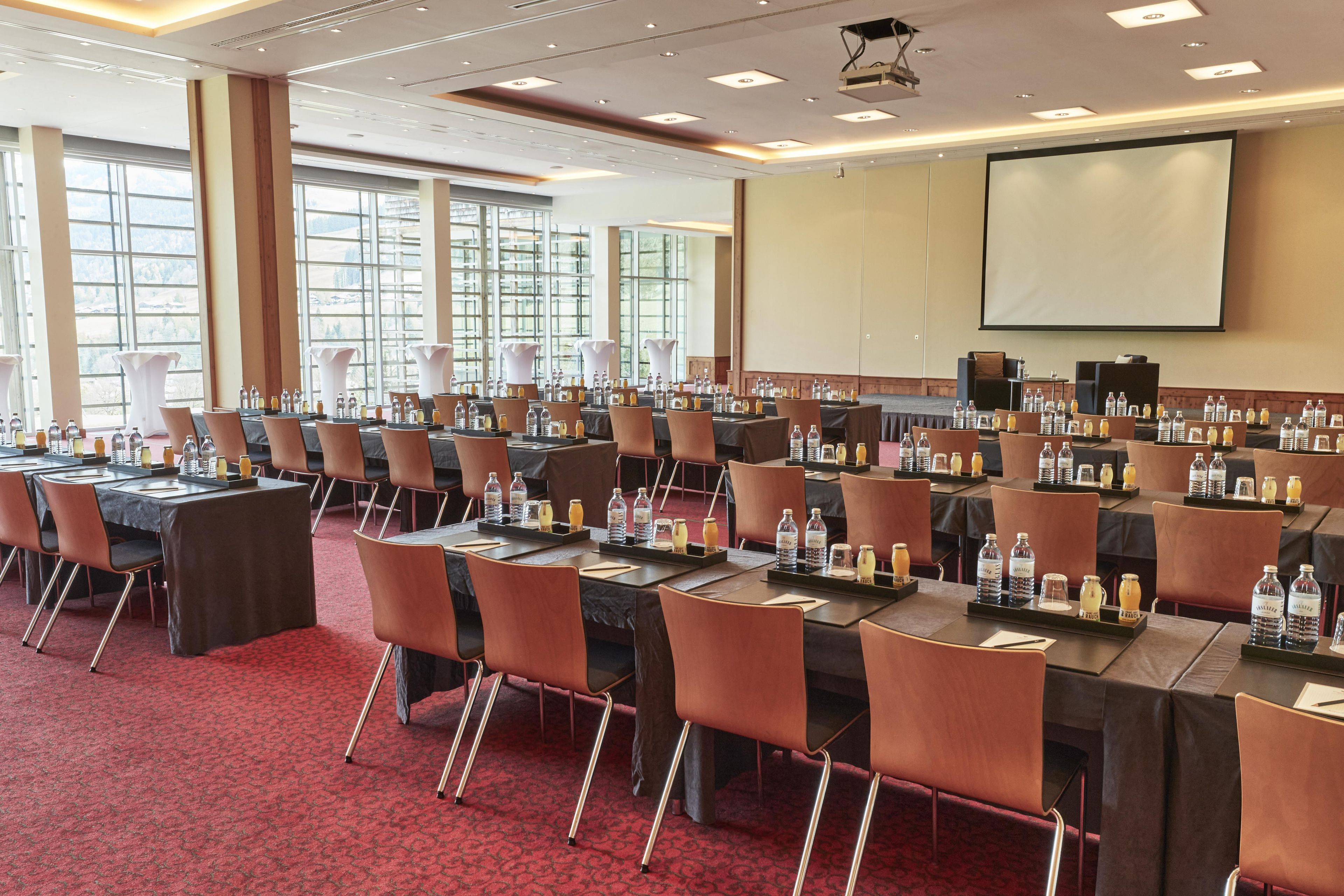 A conference room with multiple tables and chairs, equipped with water bottles and nameplates.