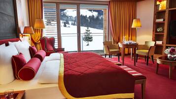 A hotel room with a large bed, a desk, a chair, and a view of a snowy landscape through the window.