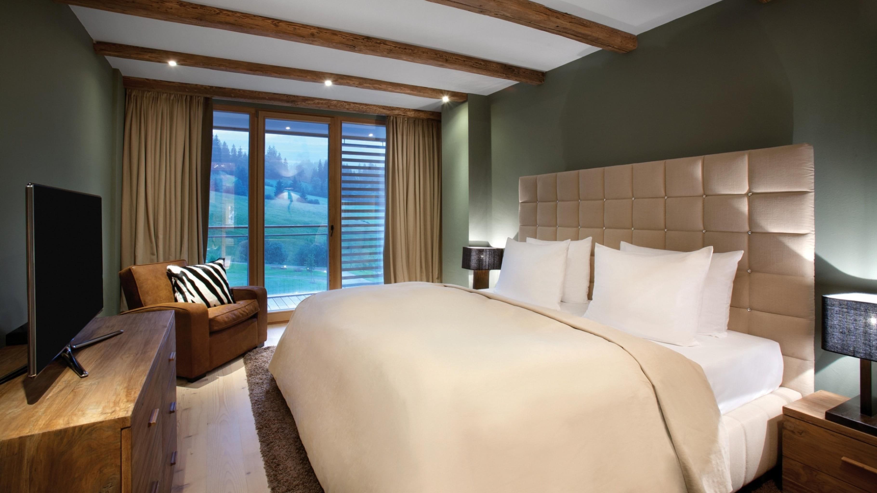 Une chambre spacieuse avec un grand lit, une tête de lit en bois, un canapé et un téléviseur.