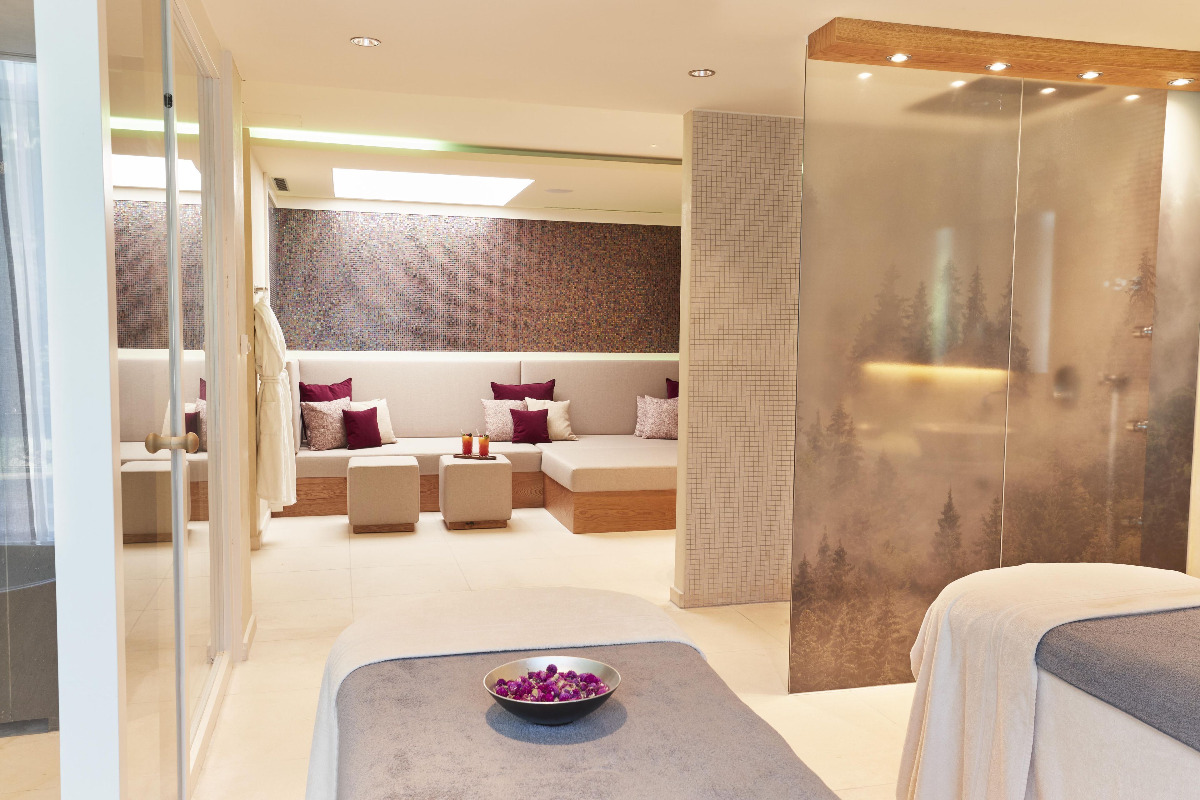 Une salle de spa moderne dotée d’un espace détente, d’une cloison en bois et d’une vue sur les arbres.