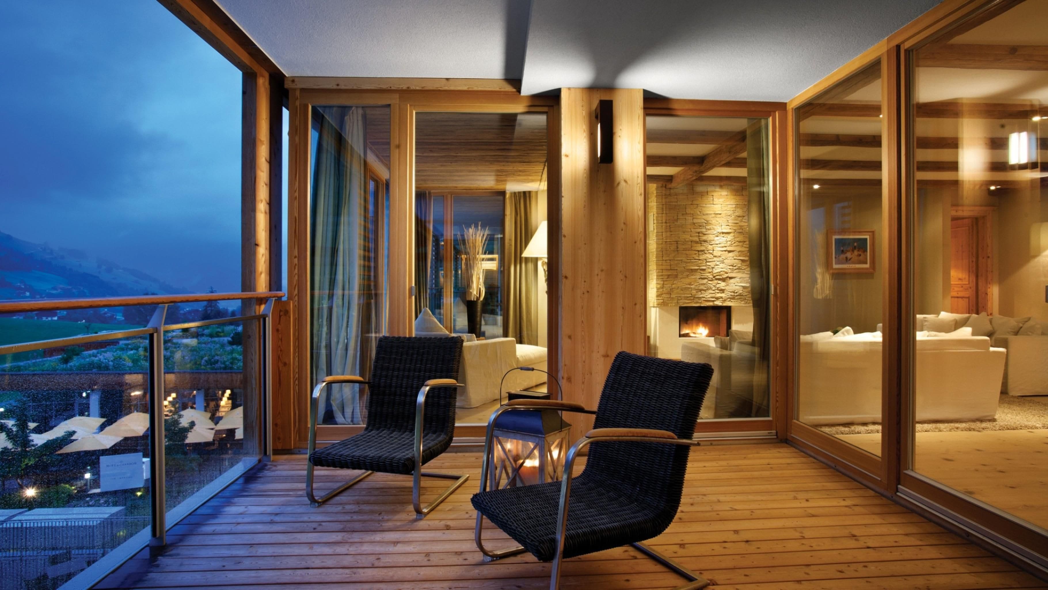 A balcony with wicker chairs, a table, and a view of the outdoors.