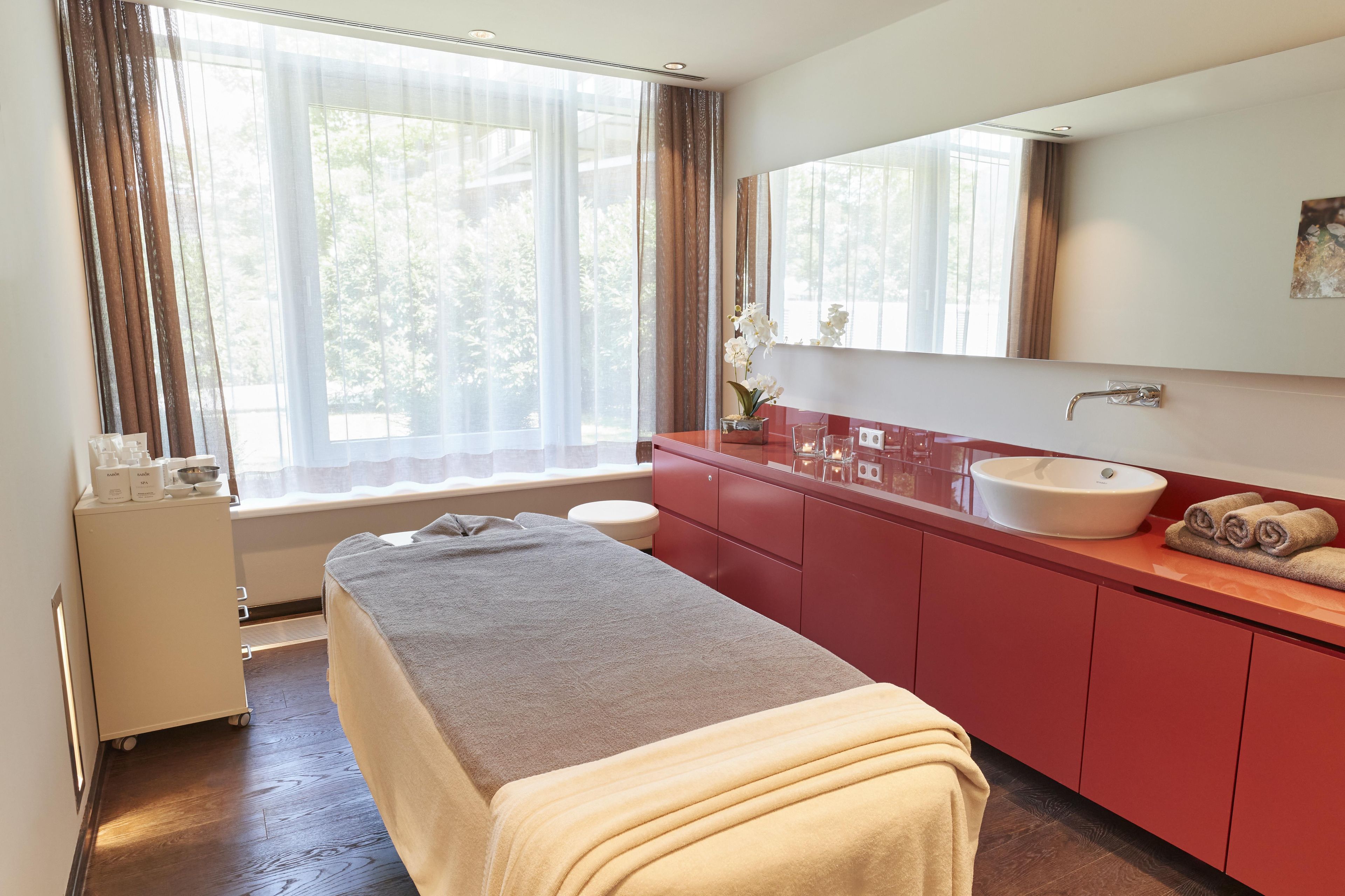 A room with a bed, a sink, and a window with curtains.