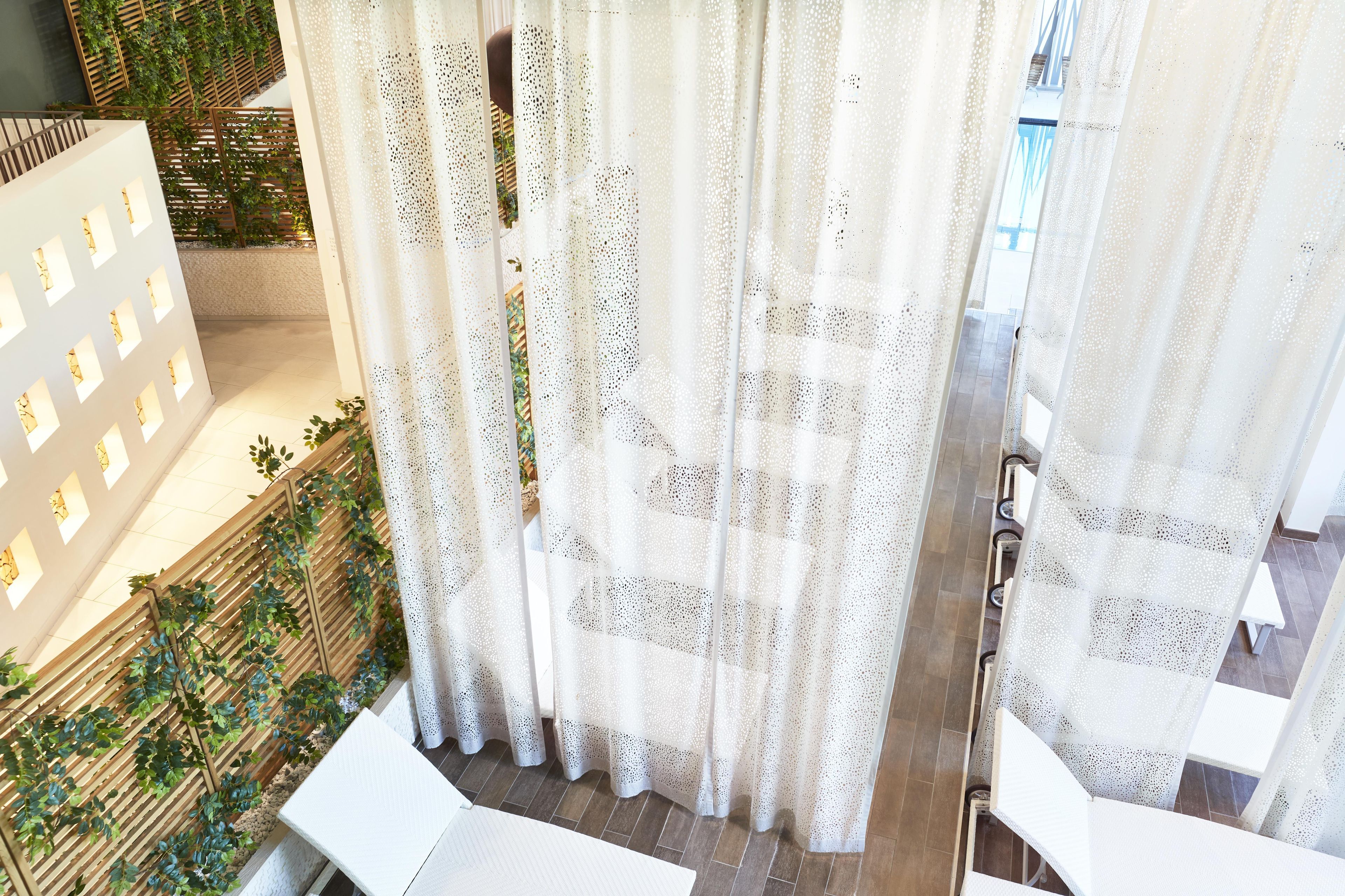 Un interior moderno con una cortina blanca, un panel de madera con espacios verdes y suelo de baldosas.