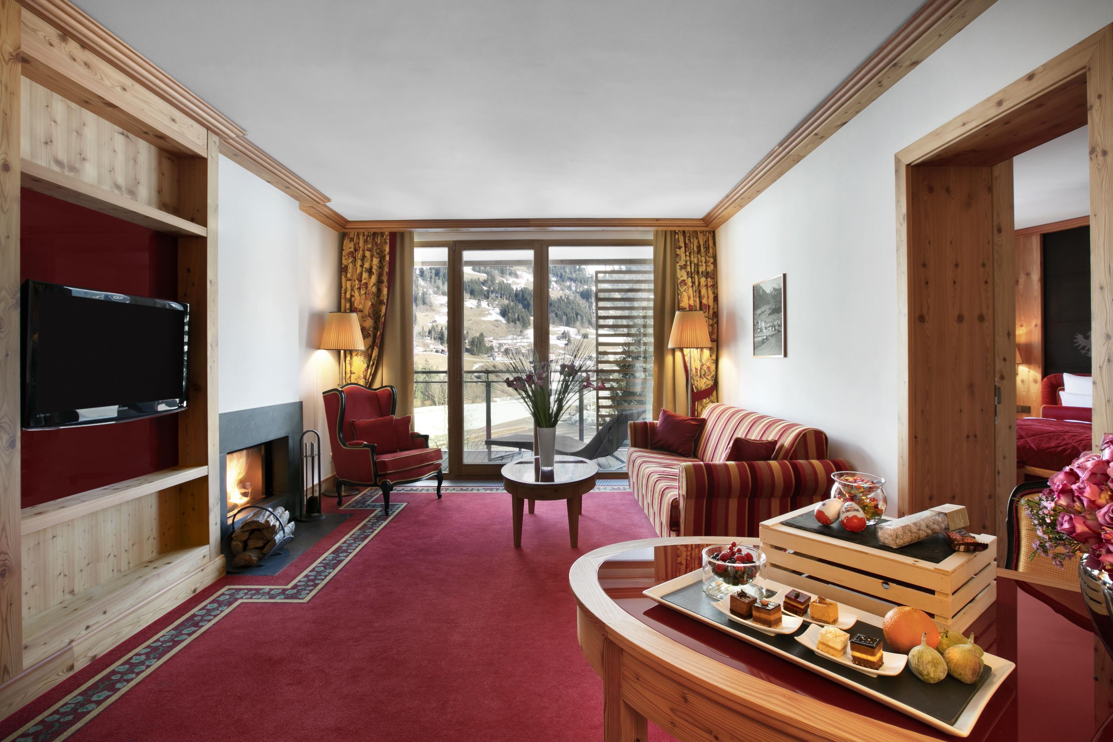 A cozy living room with a fireplace, a television, and a dining area with a tray of desserts.