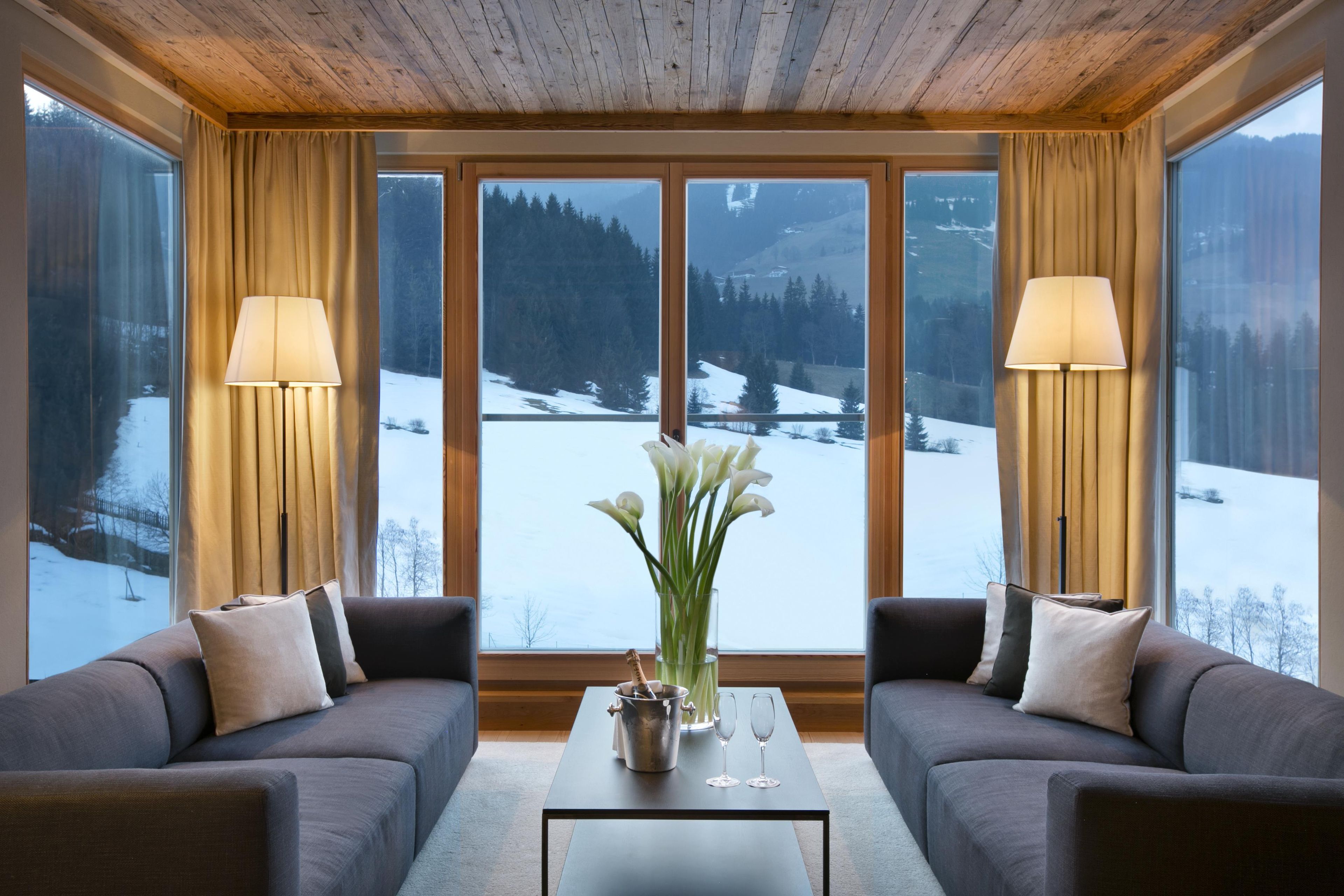 A cozy room with two sofas facing a large window overlooking a snowy landscape.