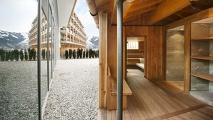 Un edificio moderno con interior de madera y grandes ventanales, con vistas a un paisaje montañoso.