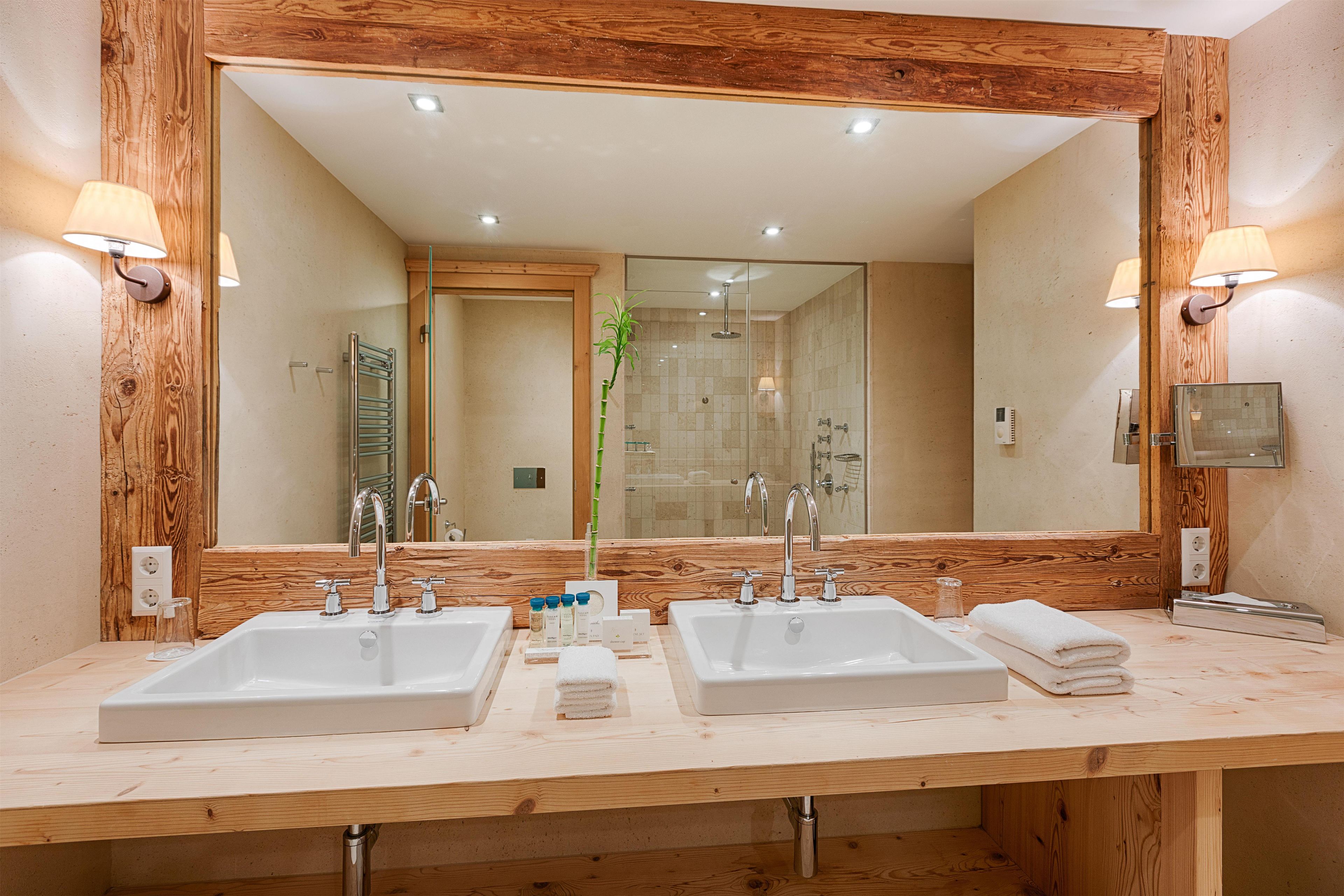 Une salle de bain avec deux lavabos, un grand miroir et un lambris en bois.