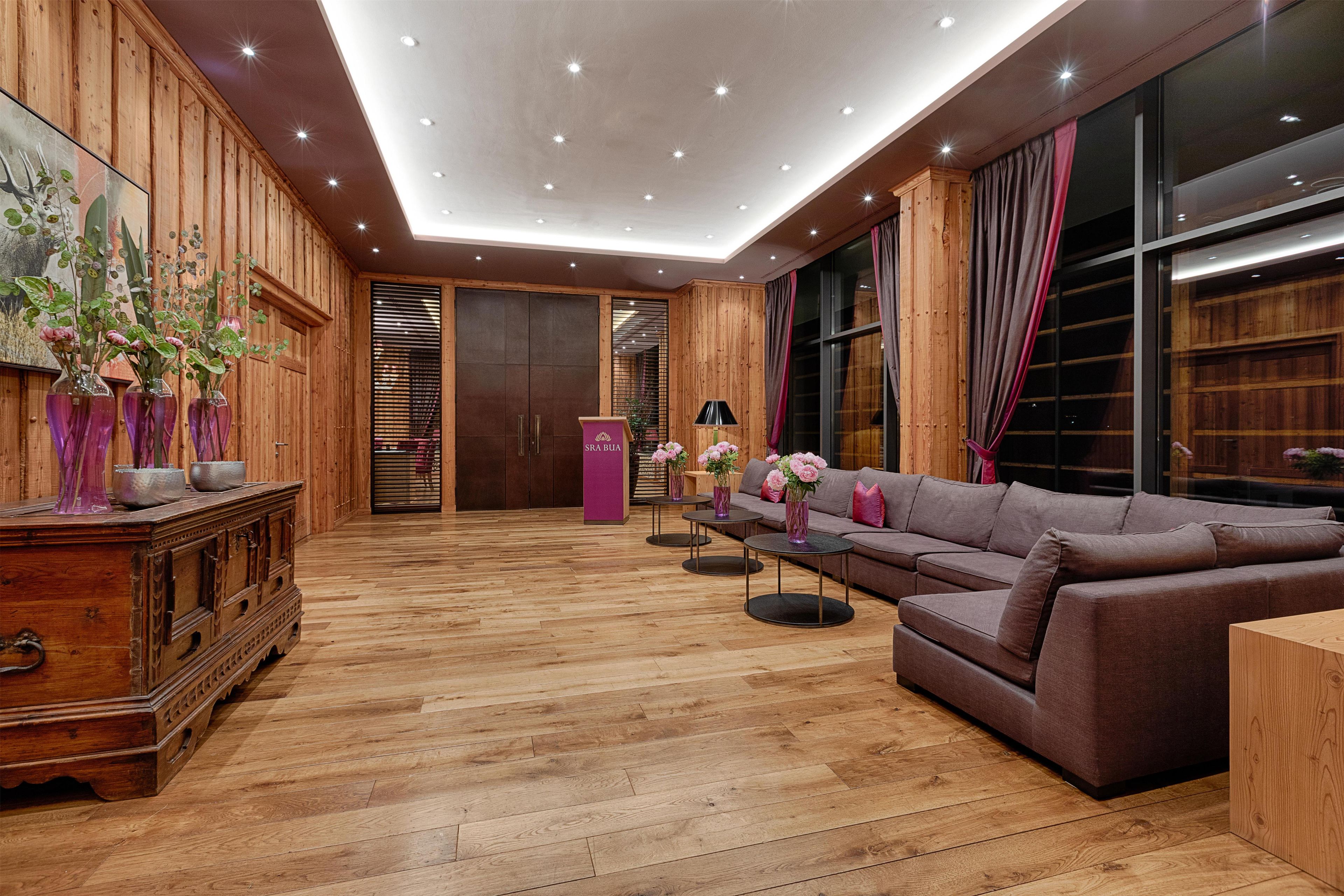 A modern interior with wooden paneling, a sectional sofa, a wooden cabinet, and a reception desk.