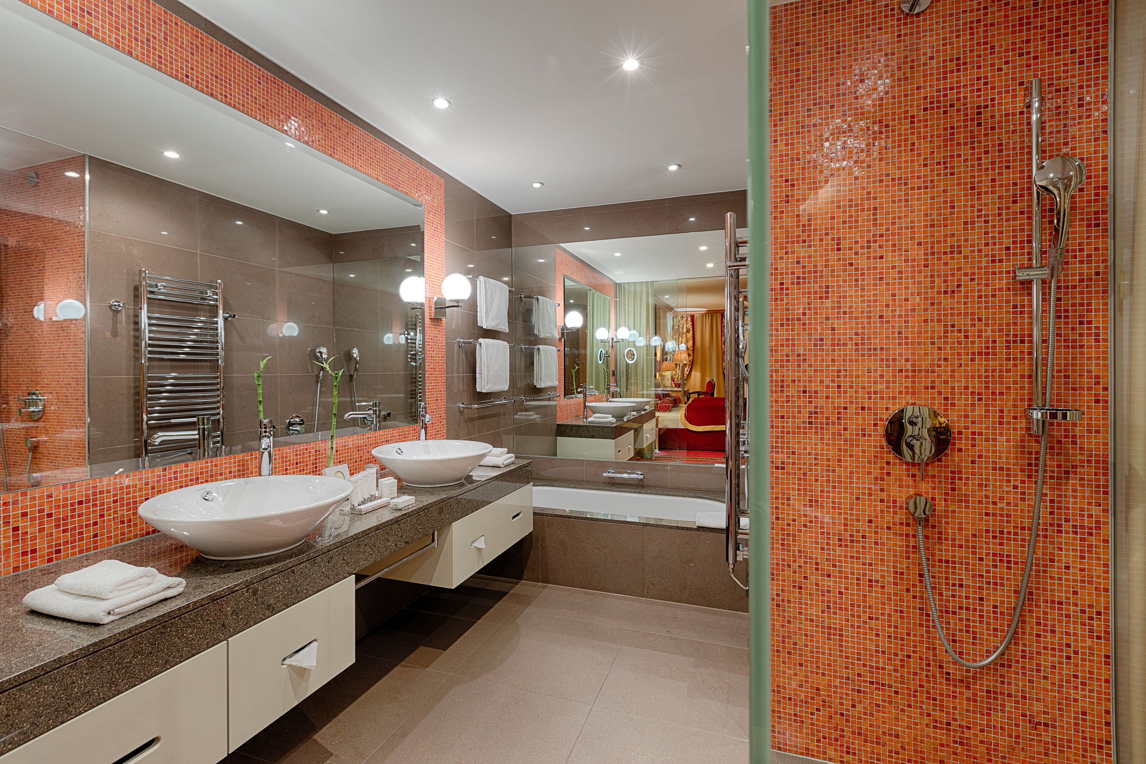Een moderne badkamer met een grote spiegel, twee wasbakken, een bad en een douche.