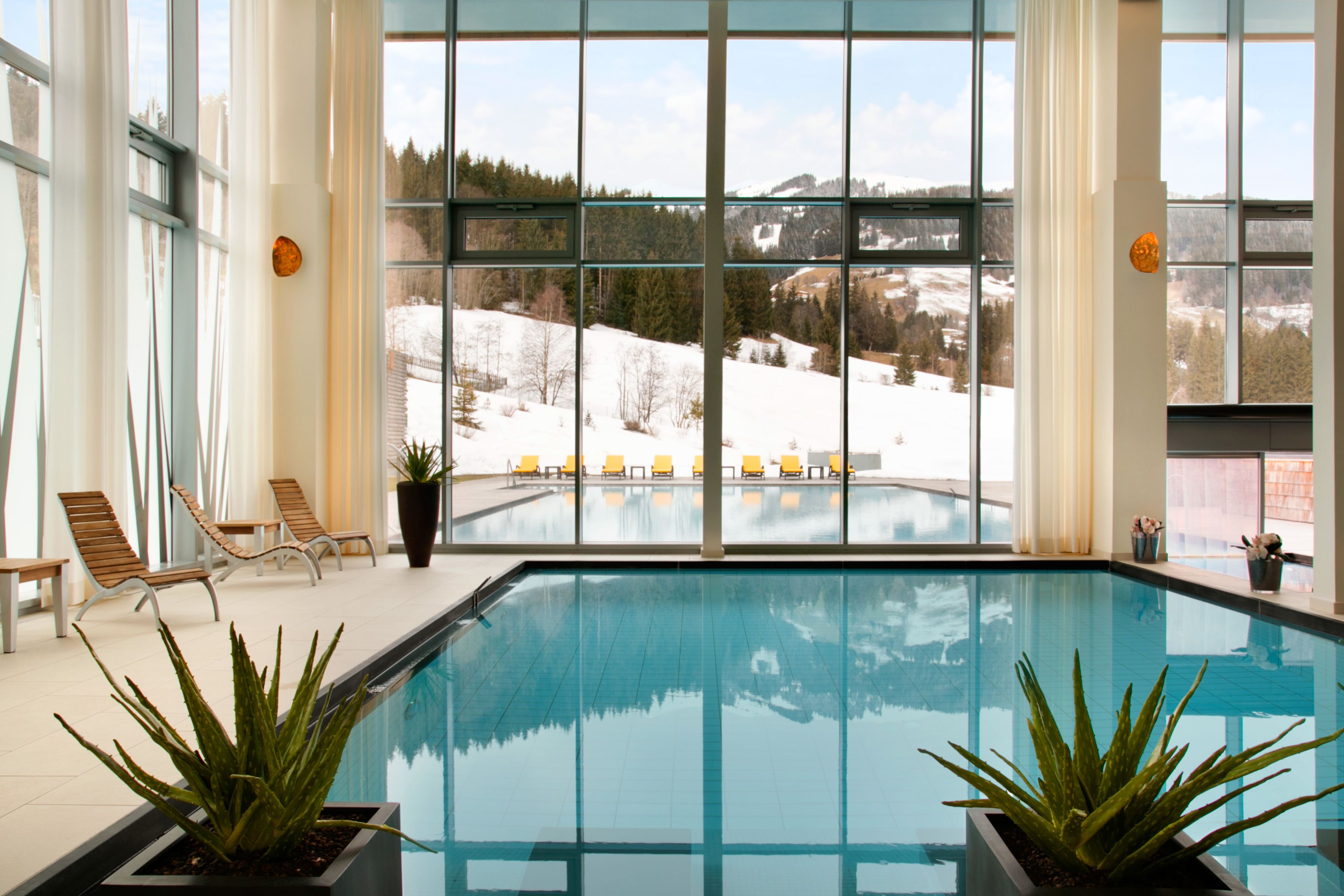 Ein Hallenbad mit freiem Blick auf eine verschneite Landschaft durch große Fenster.