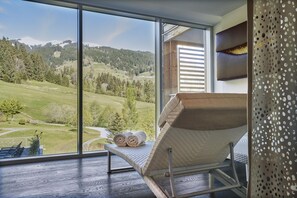 Una habitación con un ventanal amplio que ofrece vistas a un paisaje verde y montañas.