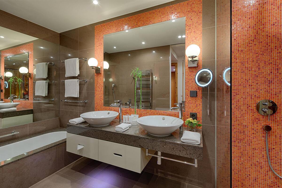 A modern bathroom with two sinks, a large mirror, and a glass shower enclosure.