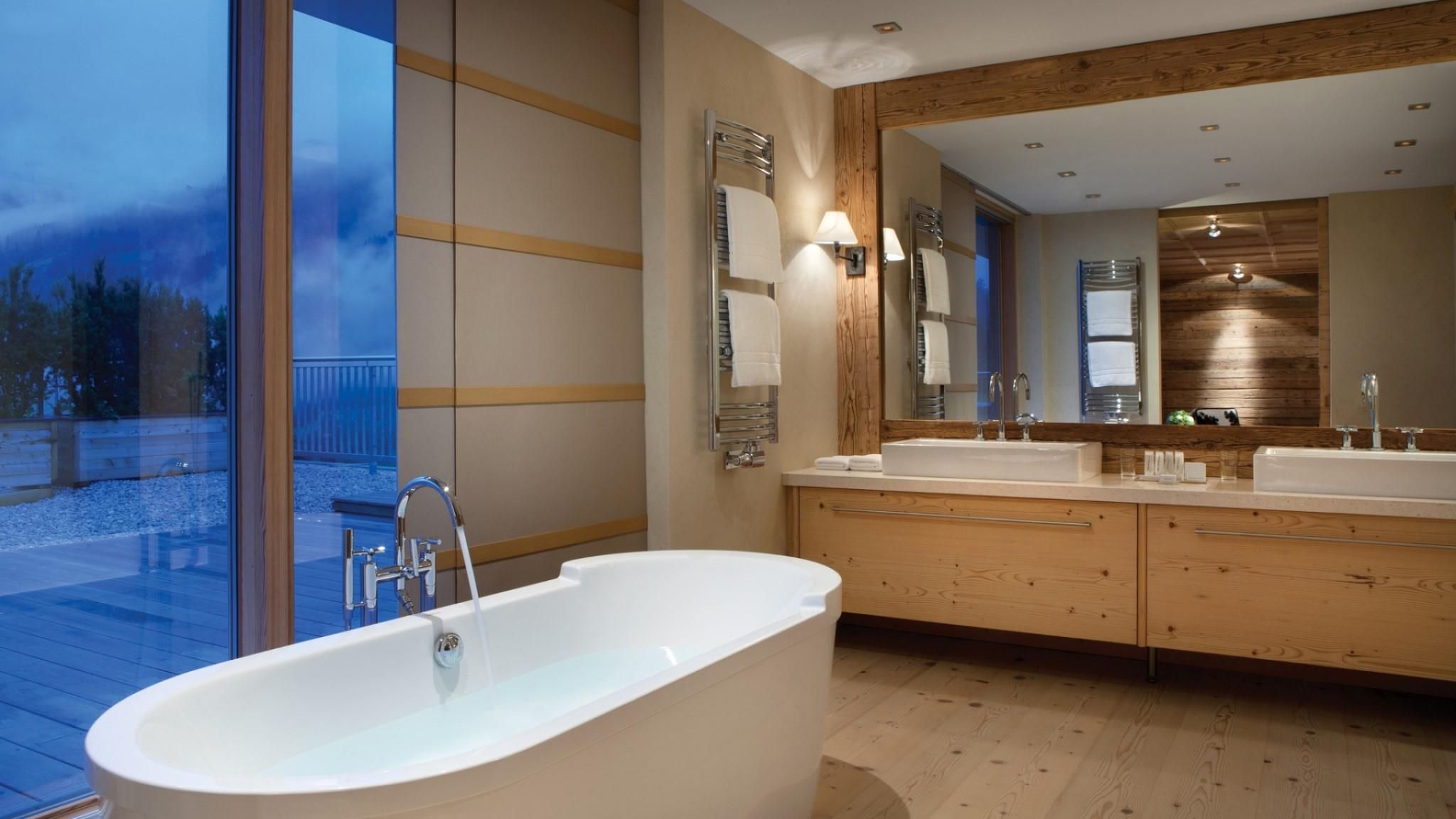 A modern bathroom with a freestanding bathtub, dual sinks, and a large mirror.