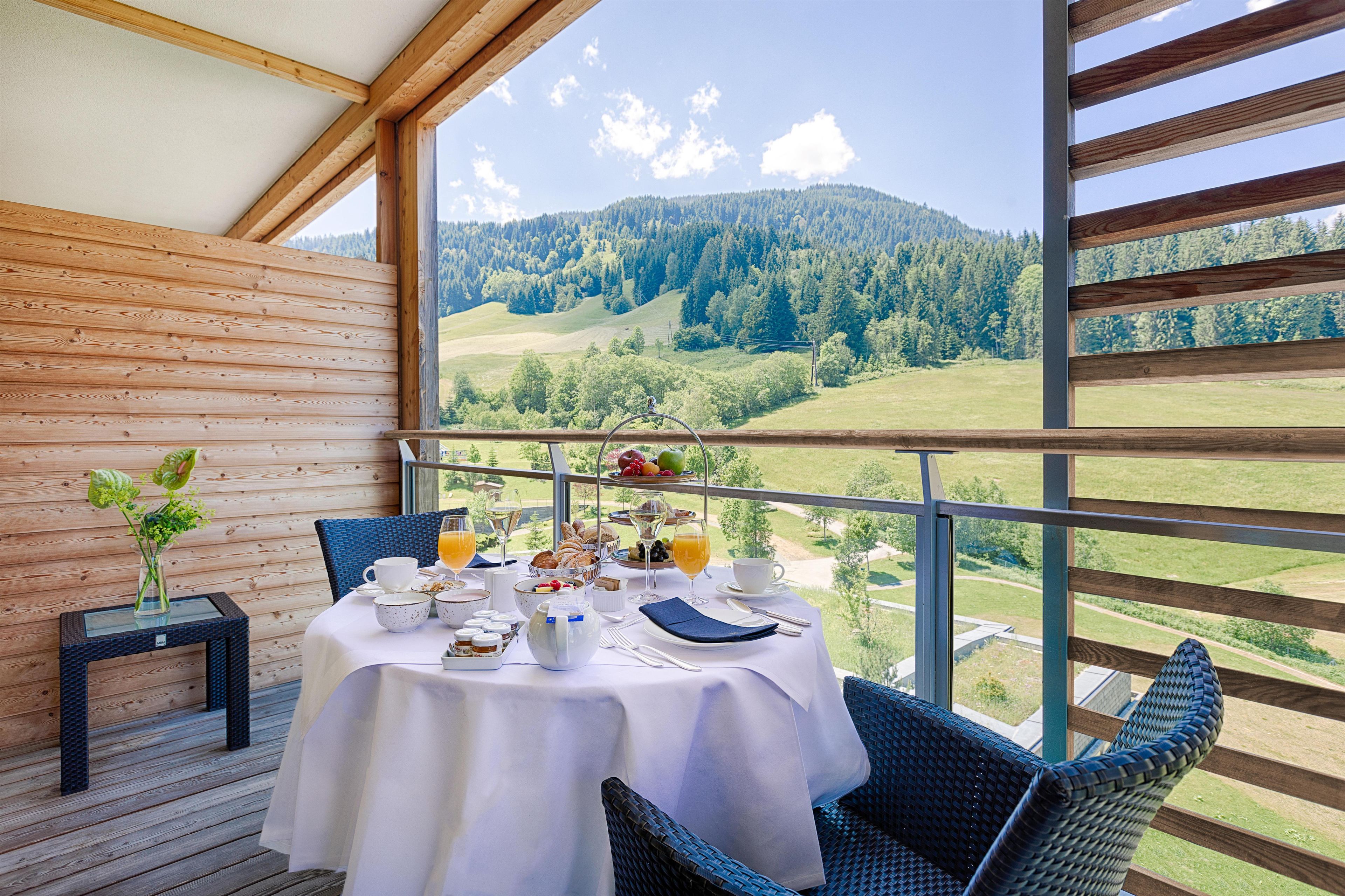 Ein Essbereich mit einem für das Frühstück gedeckten Tisch, mit Blick auf eine gebirgige Landschaft.