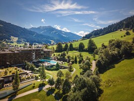 Ein Hotel mit Schwimmbad, umgeben von üppigen grünen Hügeln und Bergen.