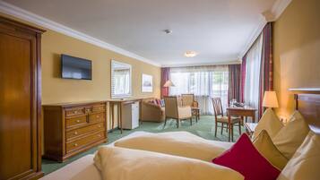 A hotel room with two beds, a desk, a chair, a television, and a window with curtains.