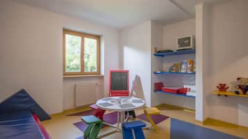 Children can play and learn in this vibrant playroom with a chalkboard, shelves, and a TV.