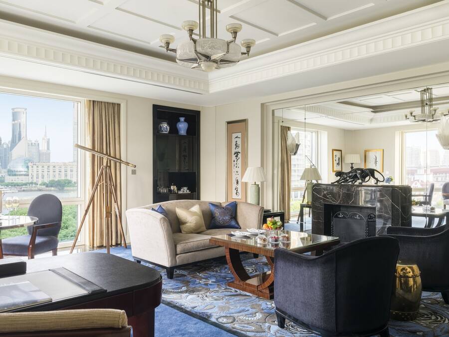 A spacious living room with a large window offering a city view, a fireplace, and a modern chandelier.