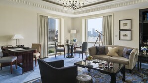 Une chambre d’hôtel dotée d’une grande fenêtre, d’un lustre, d’un canapé, d’une table basse et d’un bureau avec une lampe.