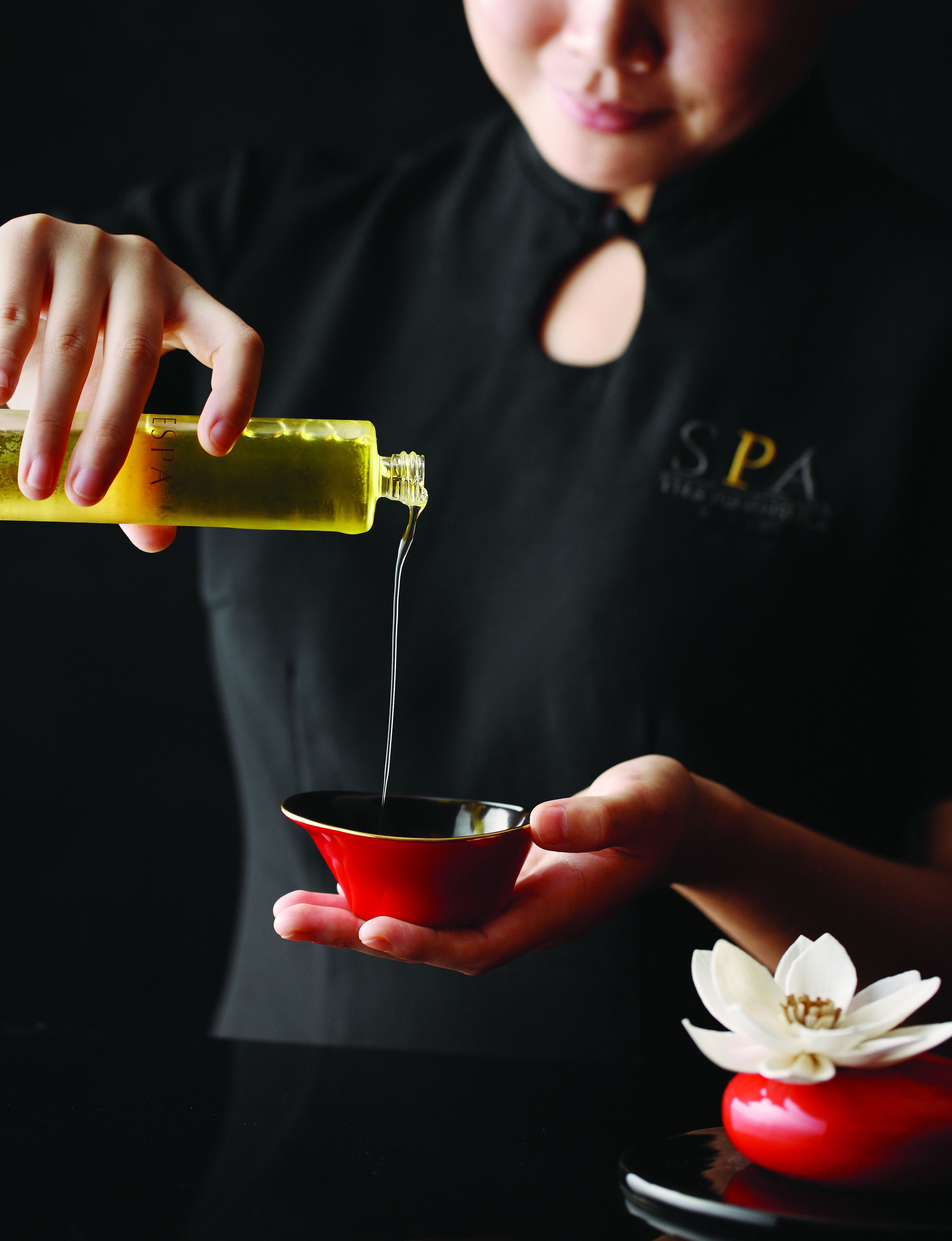 A person pouring oil into a red cup.