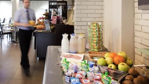 Un área de bufé con diversas opciones de comida, entre ellas frutas y aperitivos ya empacados.