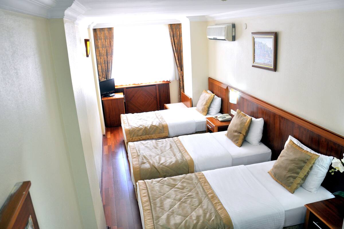 A hotel room with two beds, a desk, a chair, and a window with curtains.