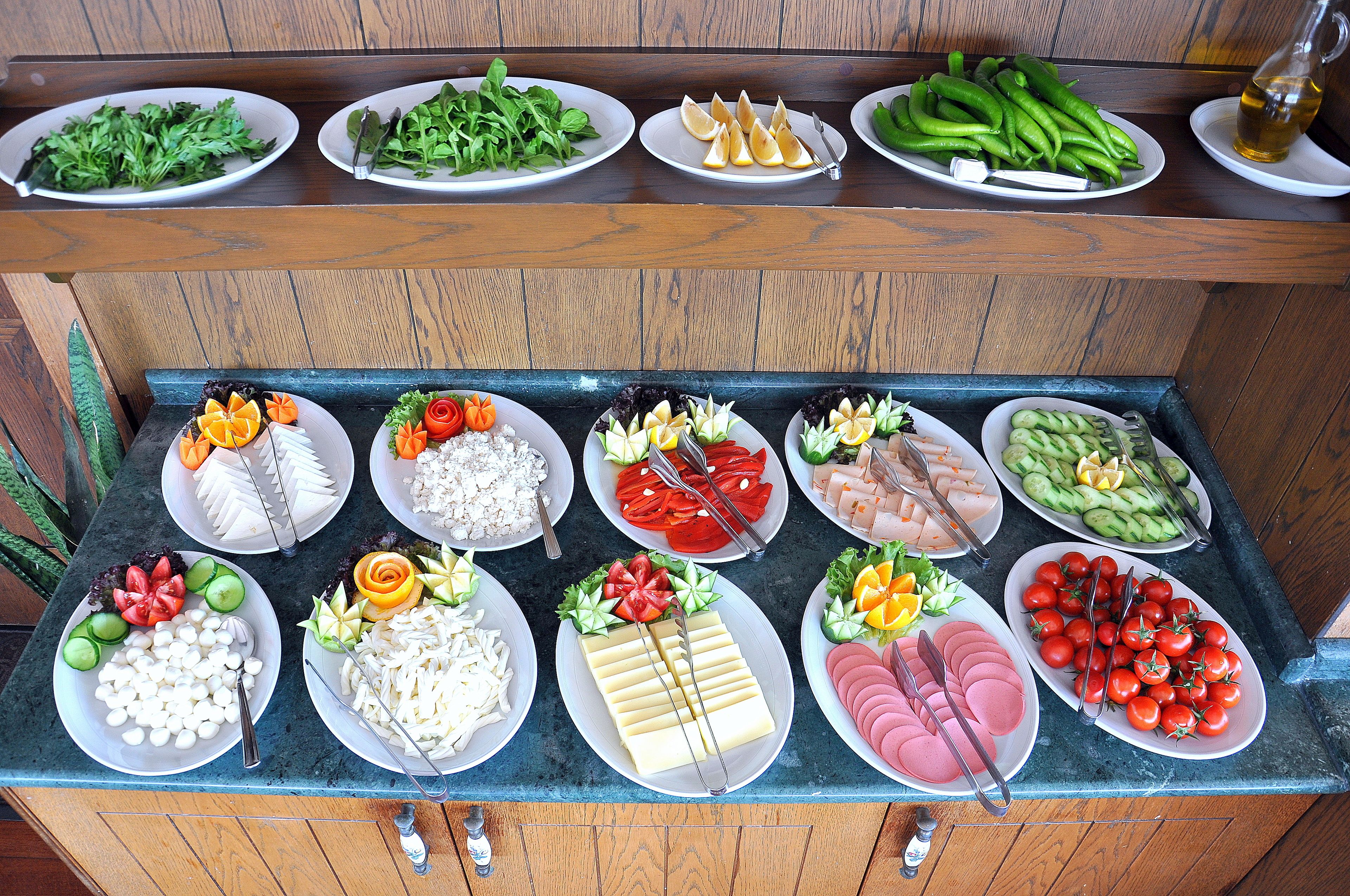 A buffet with various food items including vegetables, cheeses, and meats.