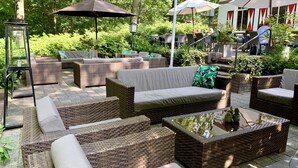 Un espace extérieur aménagé avec des meubles en osier, une table basse en verre et des parasols.
