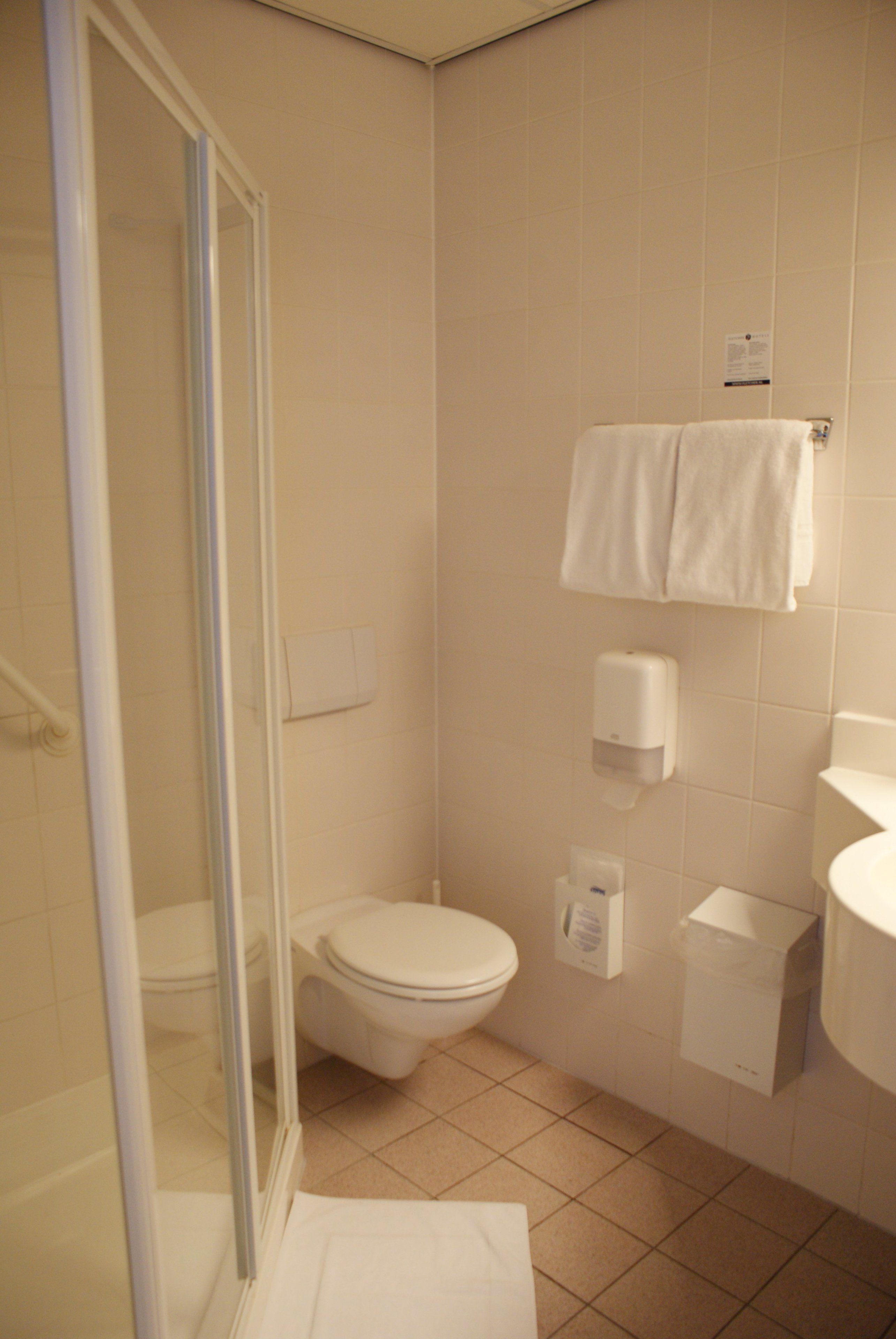 Une salle de bain comprenant des toilettes, un lavabo, un porte-serviettes et un espace douche.