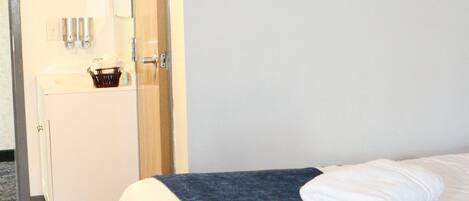 A hotel room with a bed, a bathroom with a sink and mirror, and a door leading to another room.