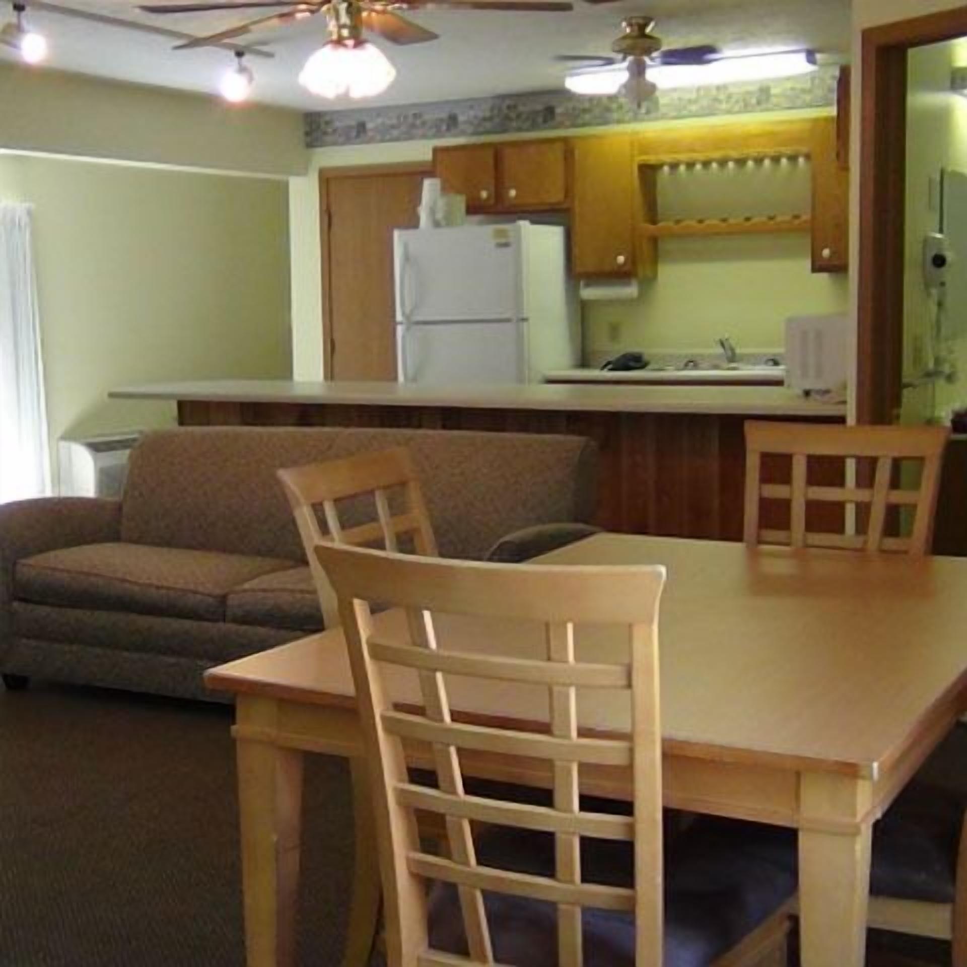 A compact living space with a kitchenette, a dining table with chairs, and a sofa.