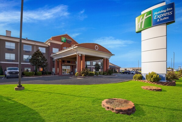 A Holiday Inn Express & Suites building with a covered entrance, a parking lot, and well-maintained lawn. - Holiday Inn Express Hotel & Suites Okmulgee by IHG (Okmulgee)