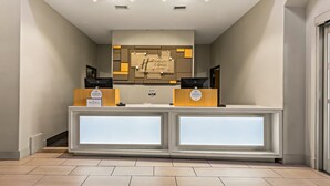 Un comptoir d’accueil au design moderne, une horloge et une enseigne indiquant le nom de l’hôtel.