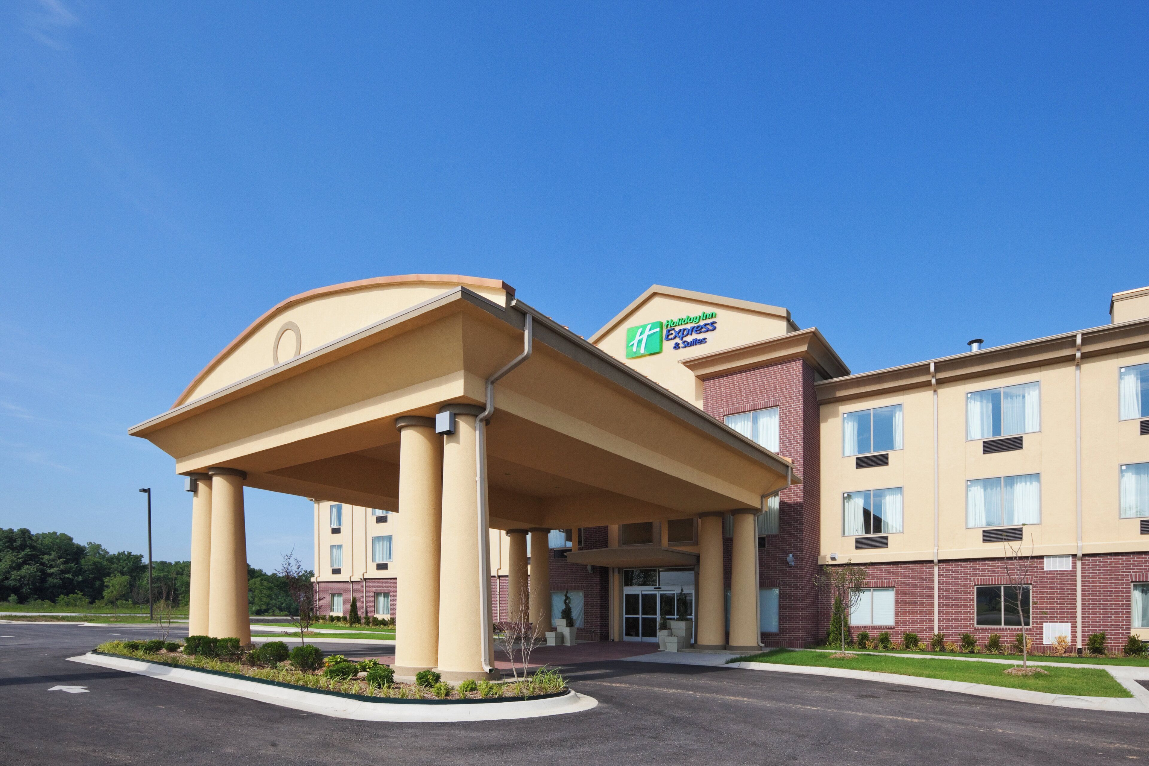 A Holiday Inn Express & Suites with a covered entrance and a brick facade.