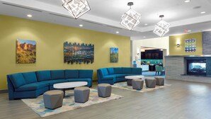Een moderne lobby met blauwe banken, een open haard en kunstwerken aan de wanden.