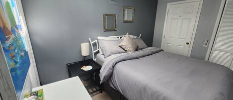 A bedroom with a bed, nightstand, and a small table with a tissue box.